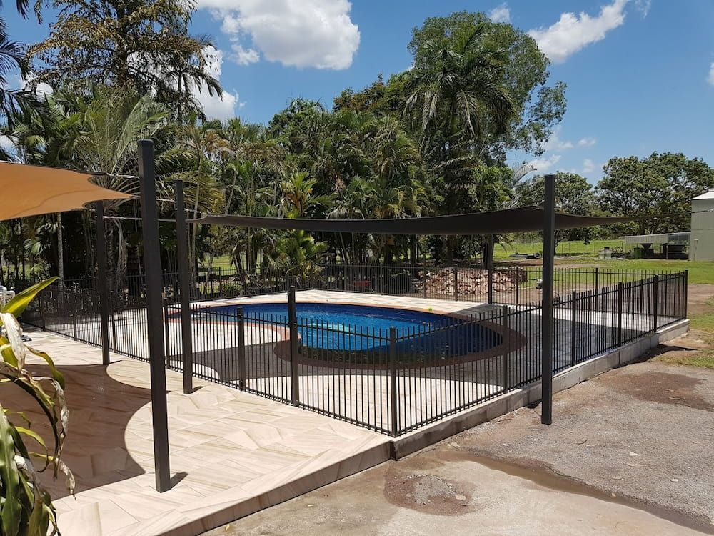A Swimming Pool Surrounded by A Fence and Trees — Fence Factory In Berrimah, NT