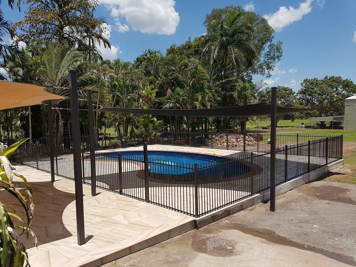 A Fence Surrounds A Swimming Pool in A Backyard — Fence Factory In Berrimah, NT
