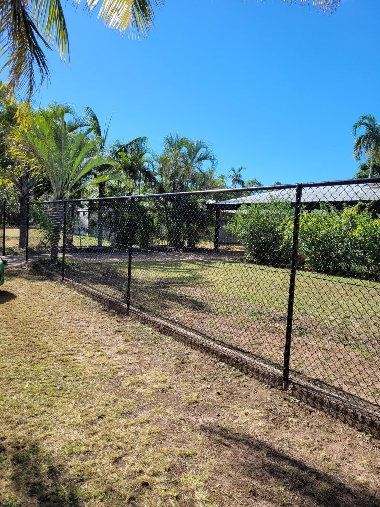 A Black Metal Fence Surrounds A Lush Green Field — Fence Factory In Berrimah, NT