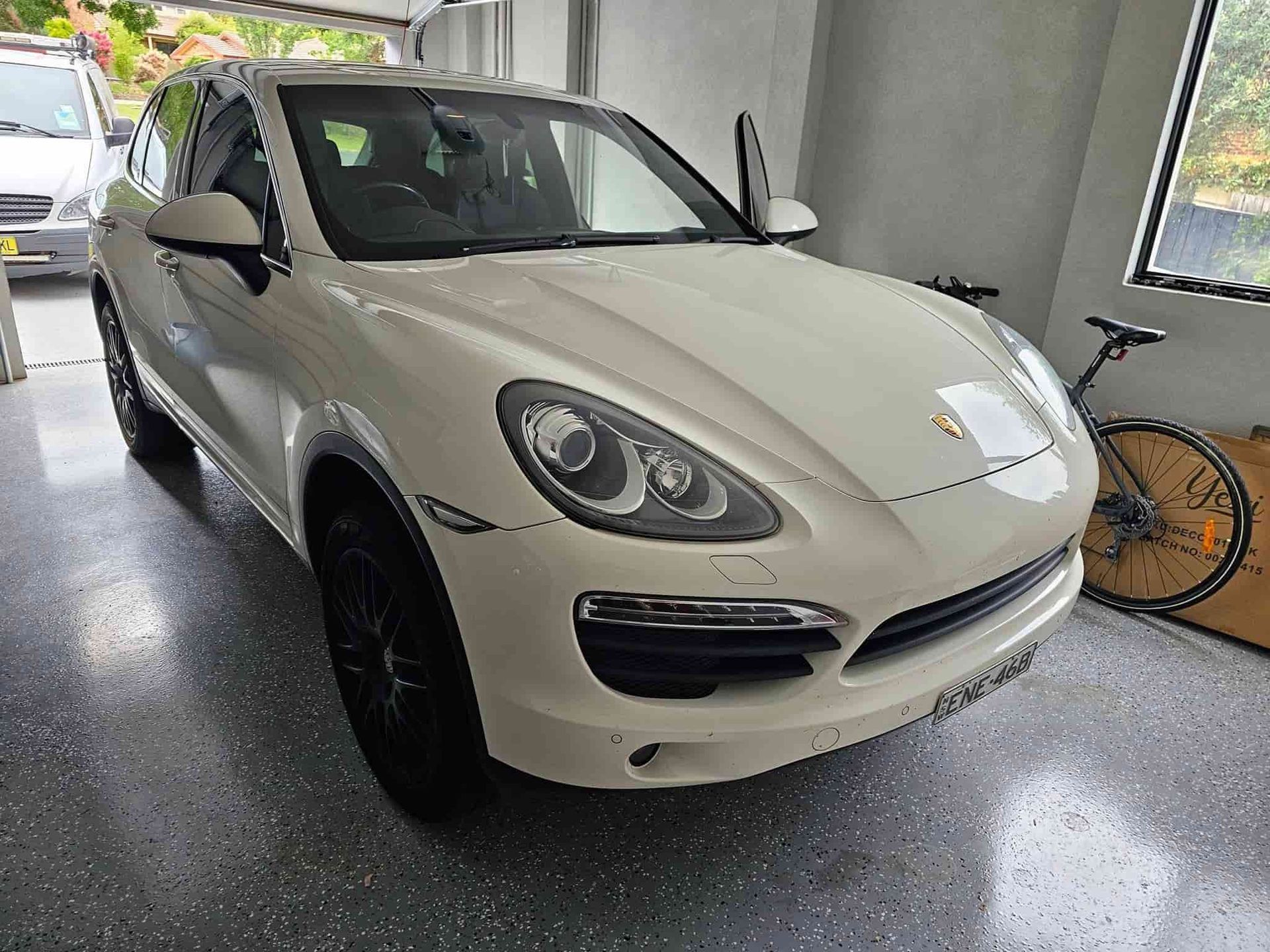 A White Porsche Cayenne Is Parked In A Garage Next To A Bicycle — Filip's Automotive in Crestwood, NSW