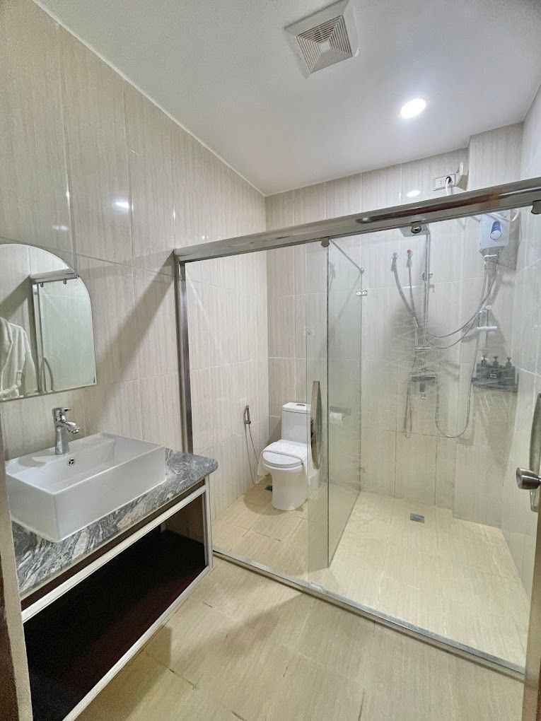 A bathroom with a sink , toilet , shower and mirror.
