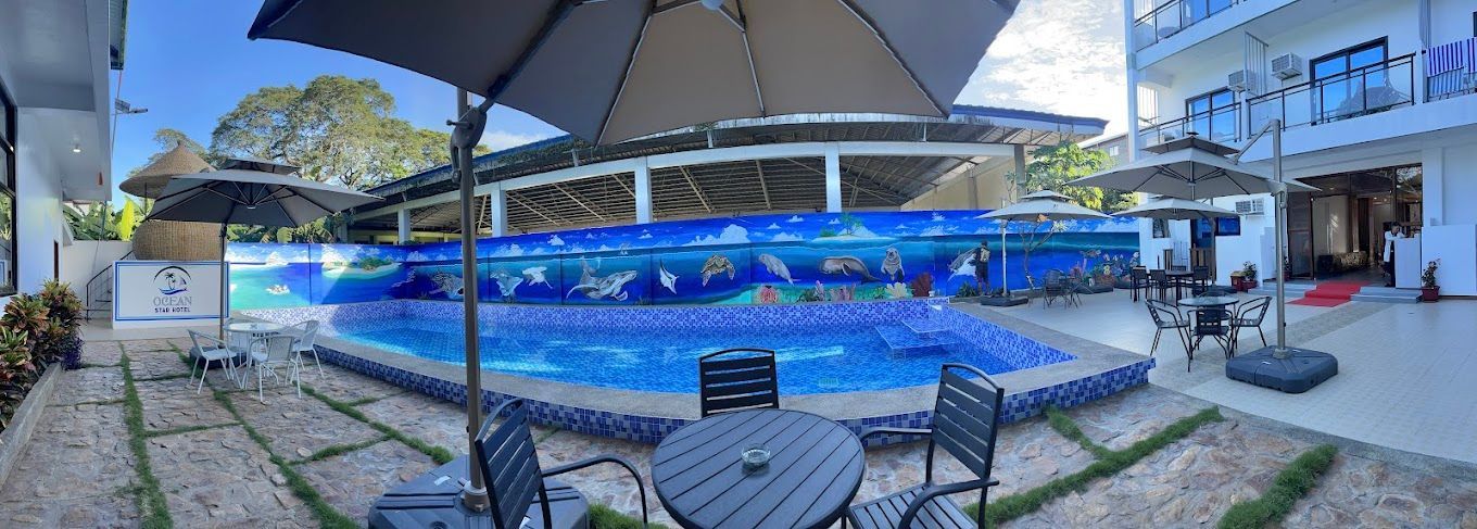 A large swimming pool with tables and chairs around it.