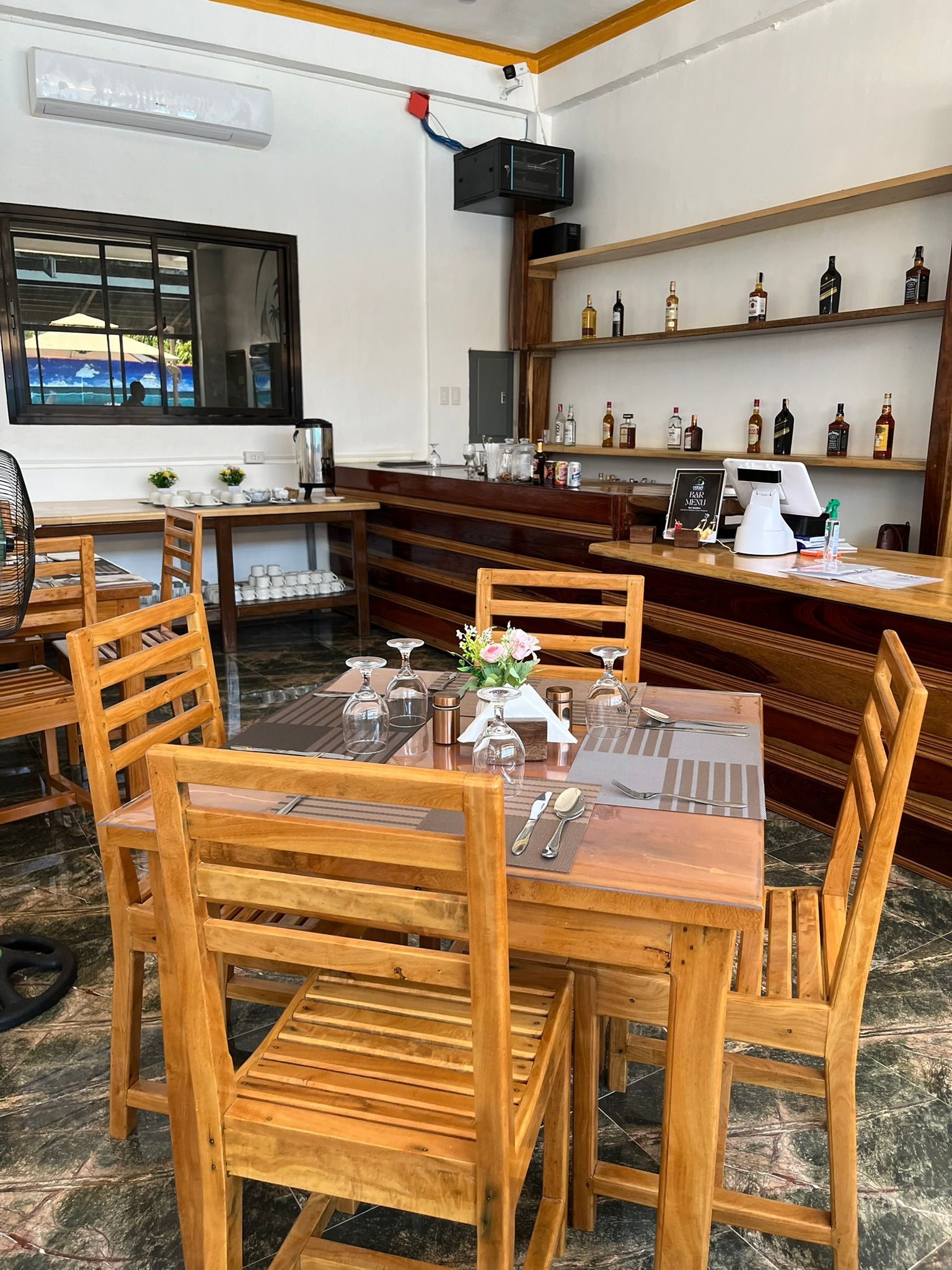 A restaurant with wooden tables and chairs and a bar.