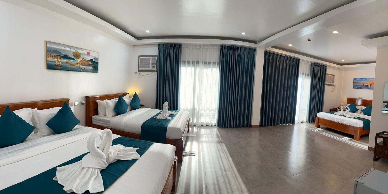 A hotel room with three beds and a large window.