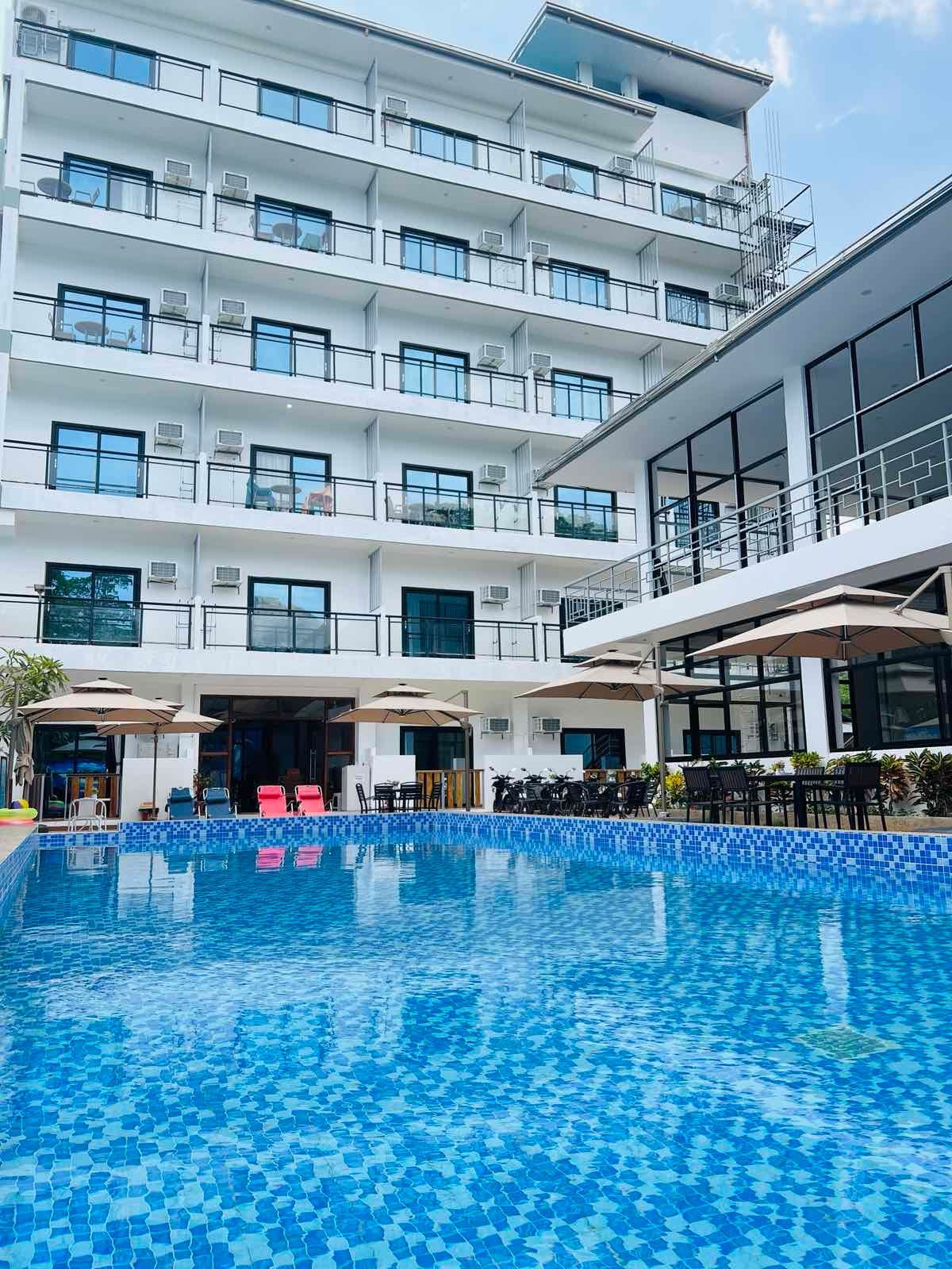 A large hotel with a large swimming pool in front of it.