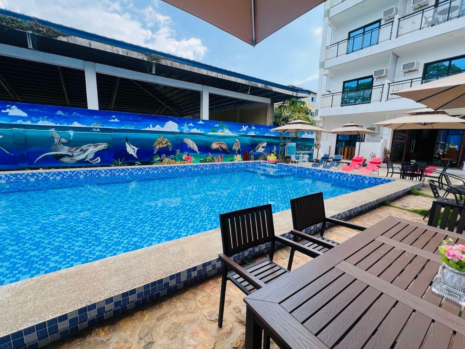 A large swimming pool with a table and chairs in front of it.
