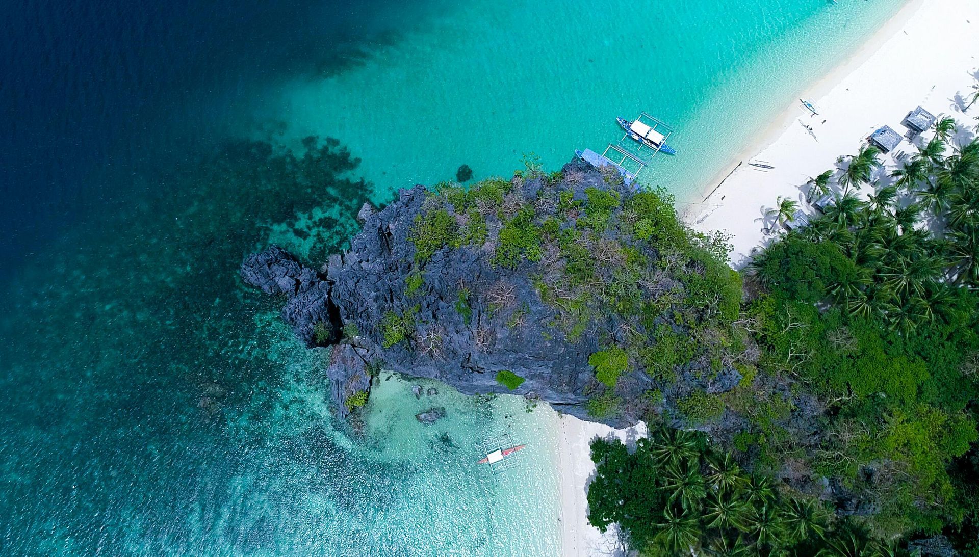 An aerial view of a tropical beach with a boat in the water.