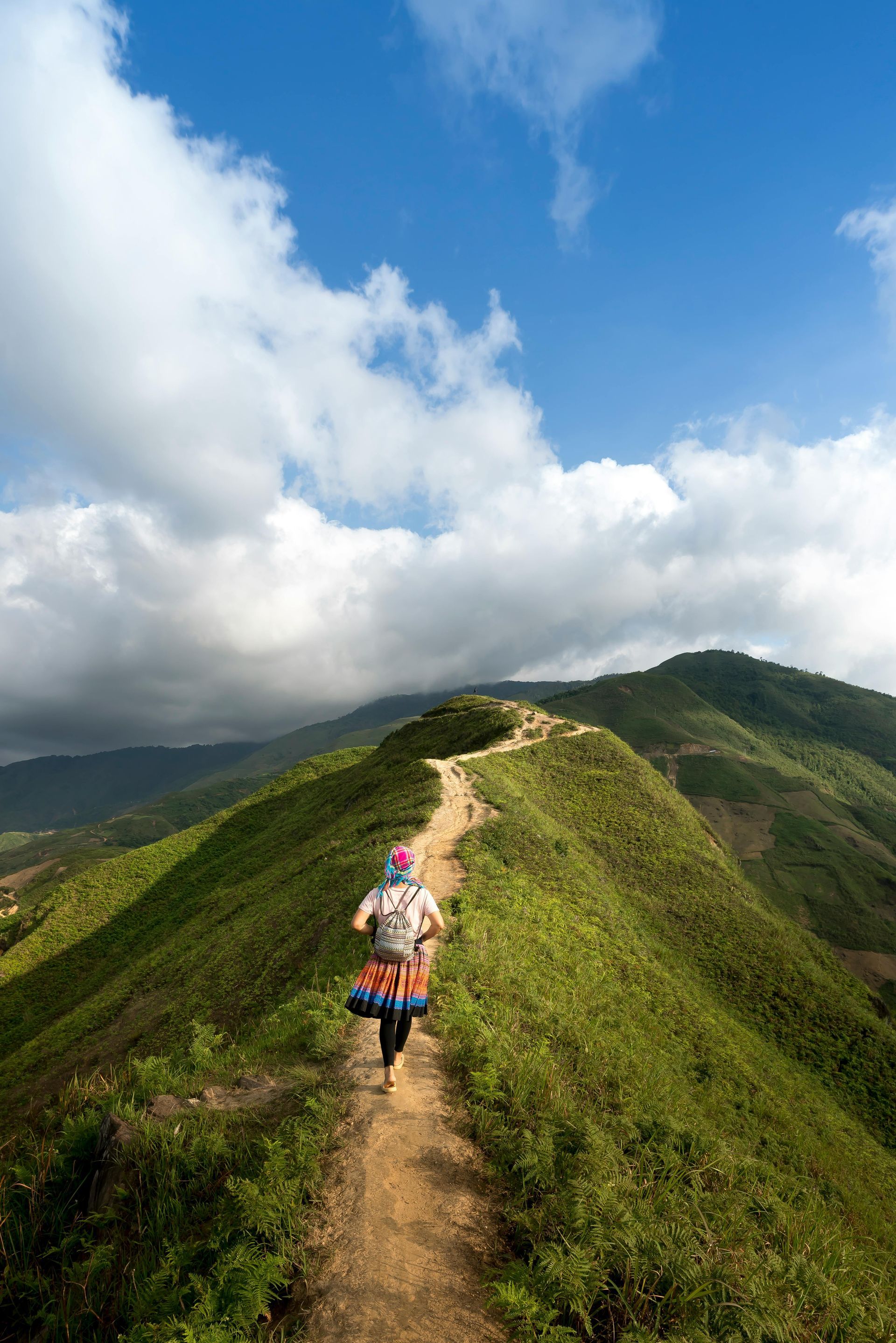 A person is walking up a hill on a dirt path.