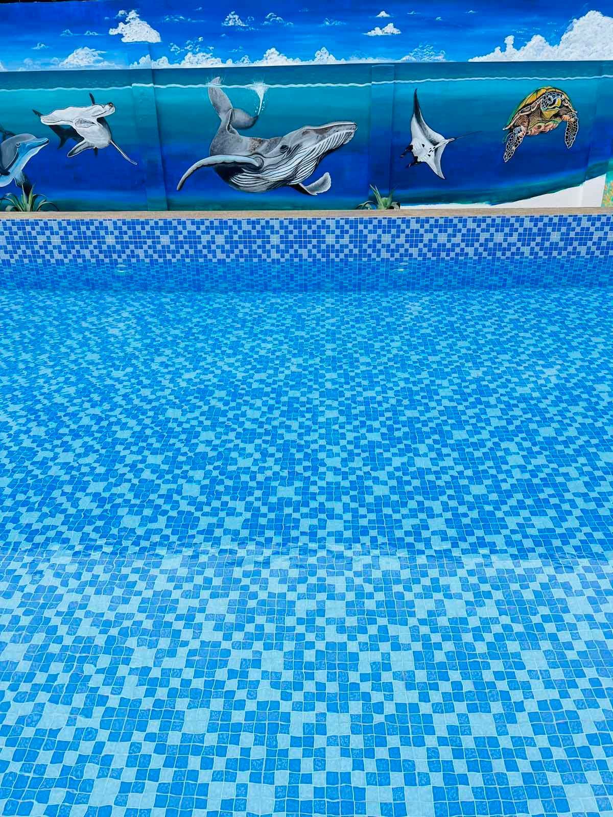 A swimming pool with a mural of sea animals on the wall.
