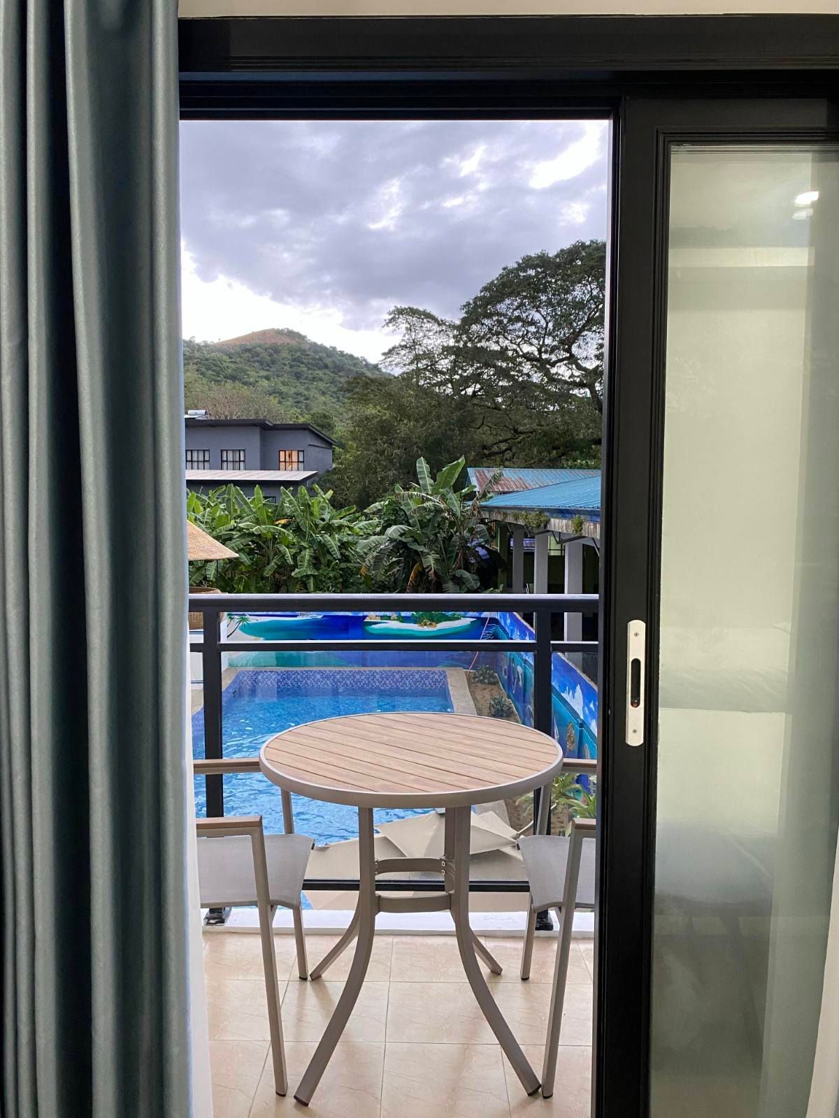 A balcony with a table and chairs overlooking a swimming pool.