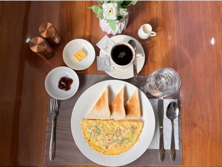 A wooden table topped with plates of food and a cup of coffee.