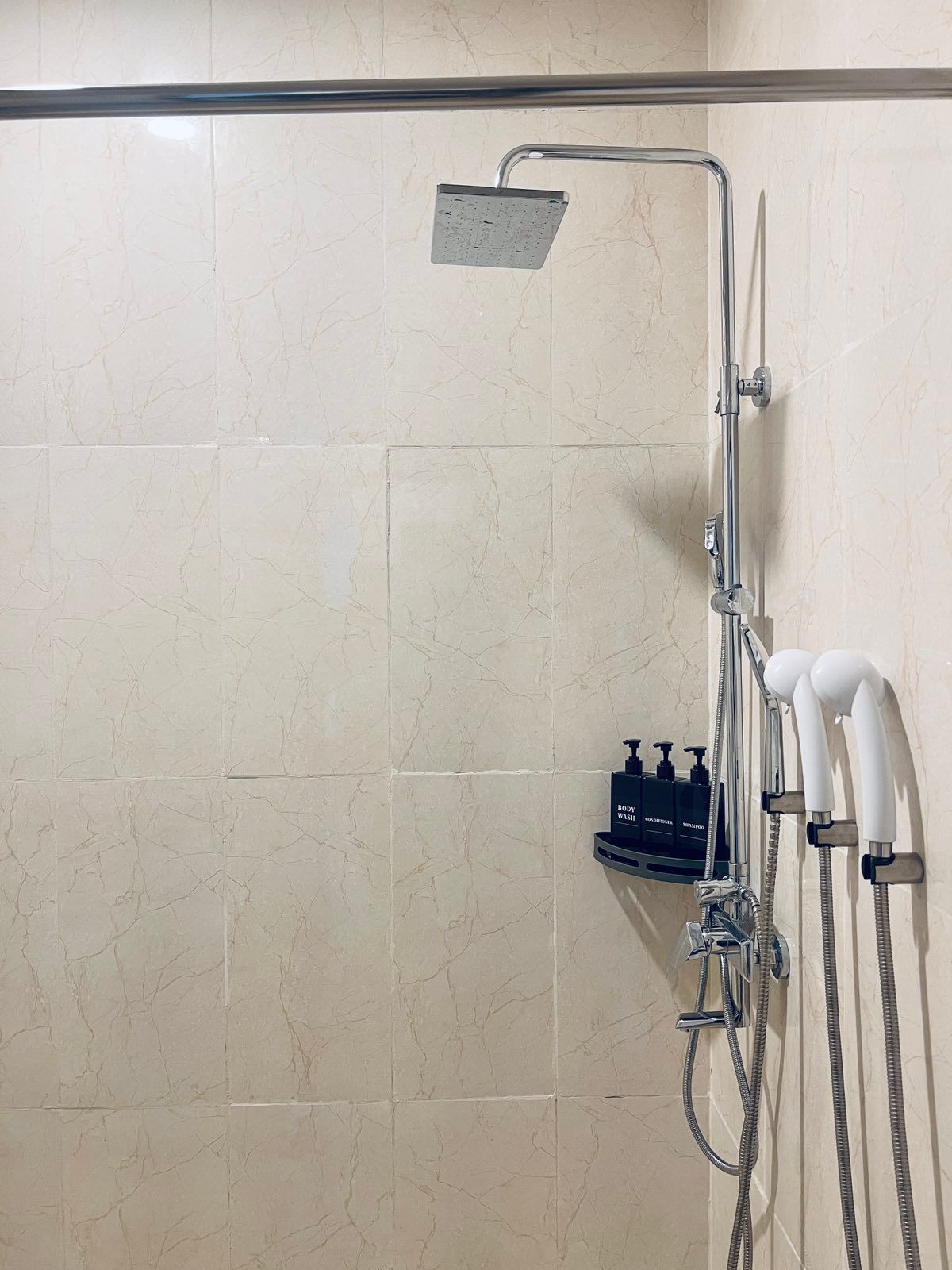 A bathroom with a shower head and soap dispensers on the wall.