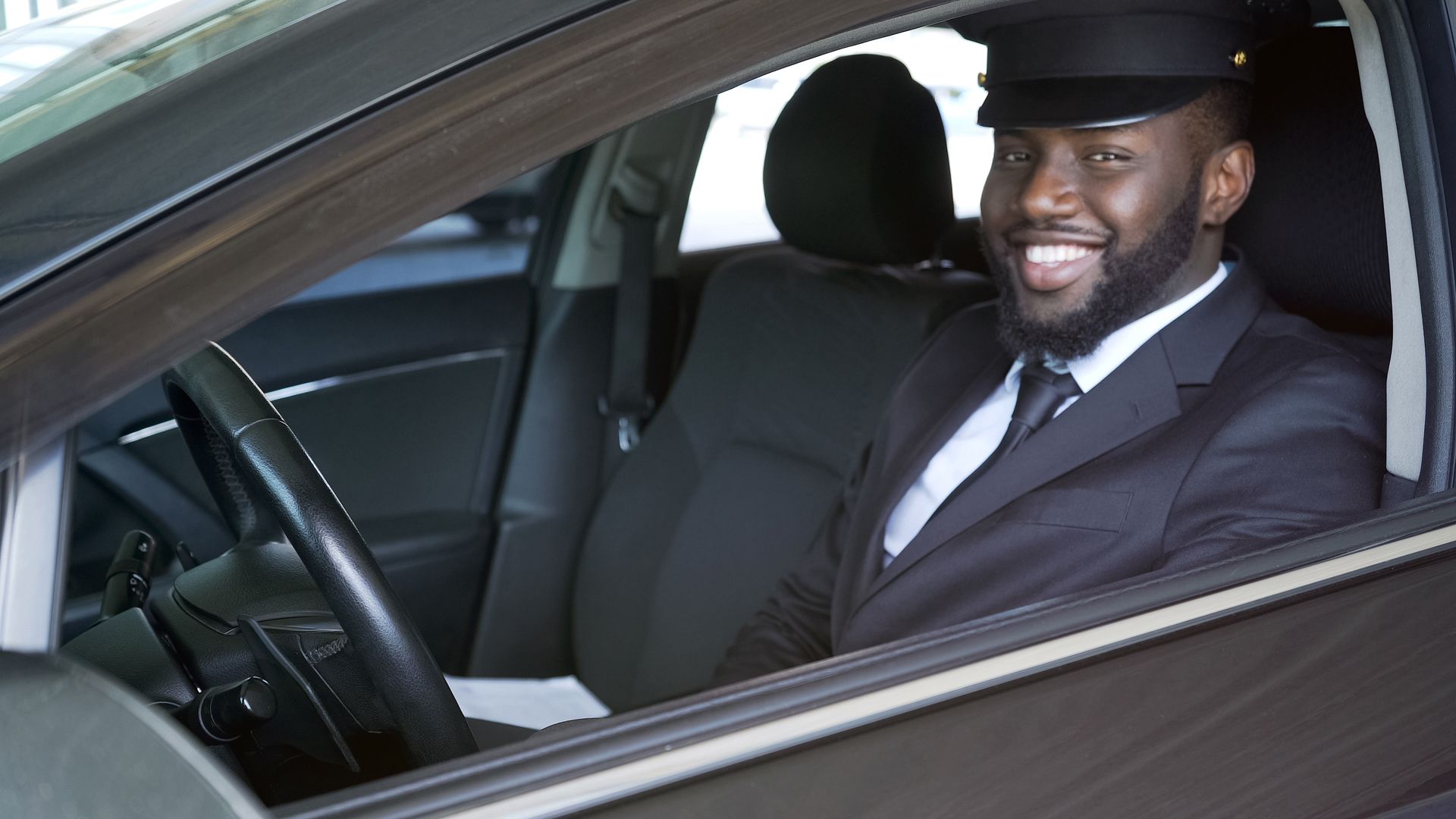 A man in a suit and tie is sitting in the driver 's seat of a car