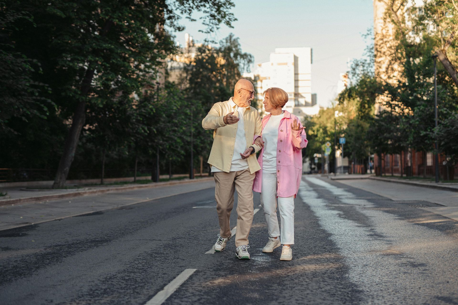 Couple dancing joyfully in the middle of a city street. The man wears beige, the woman pink.