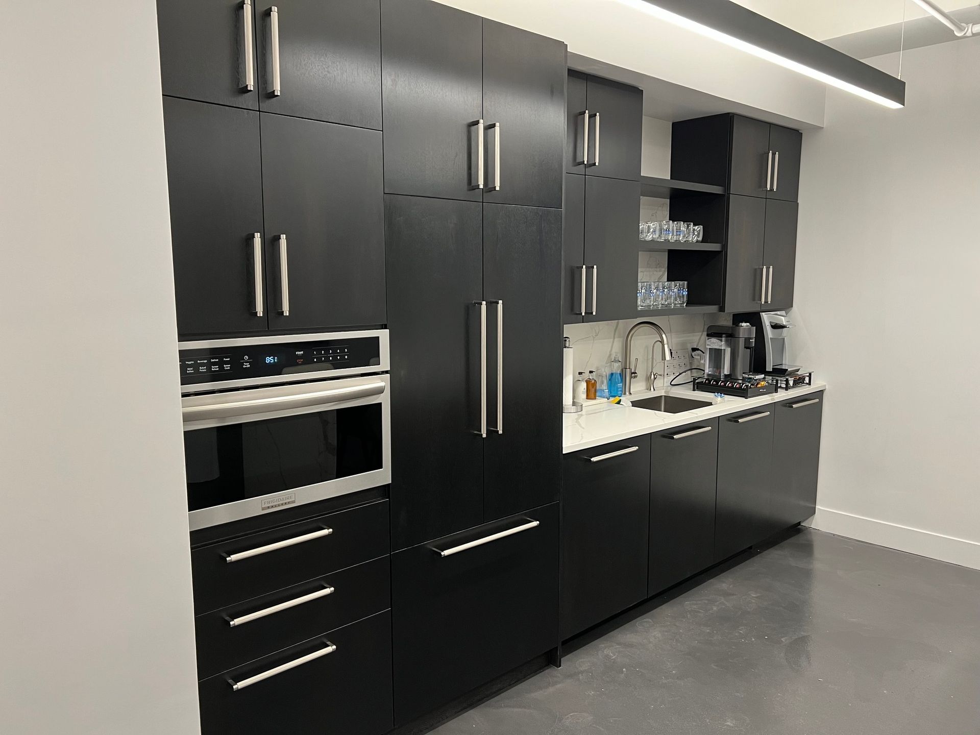 Modern black kitchen with stainless steel appliances and hardware.