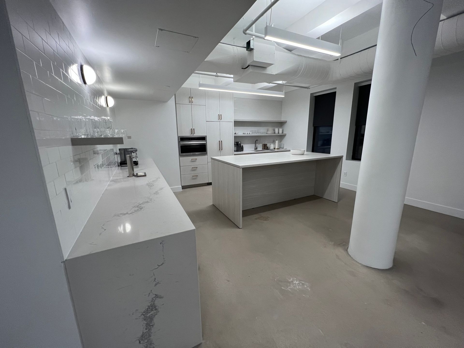 Modern white kitchen with island, countertops, and stainless steel appliances.