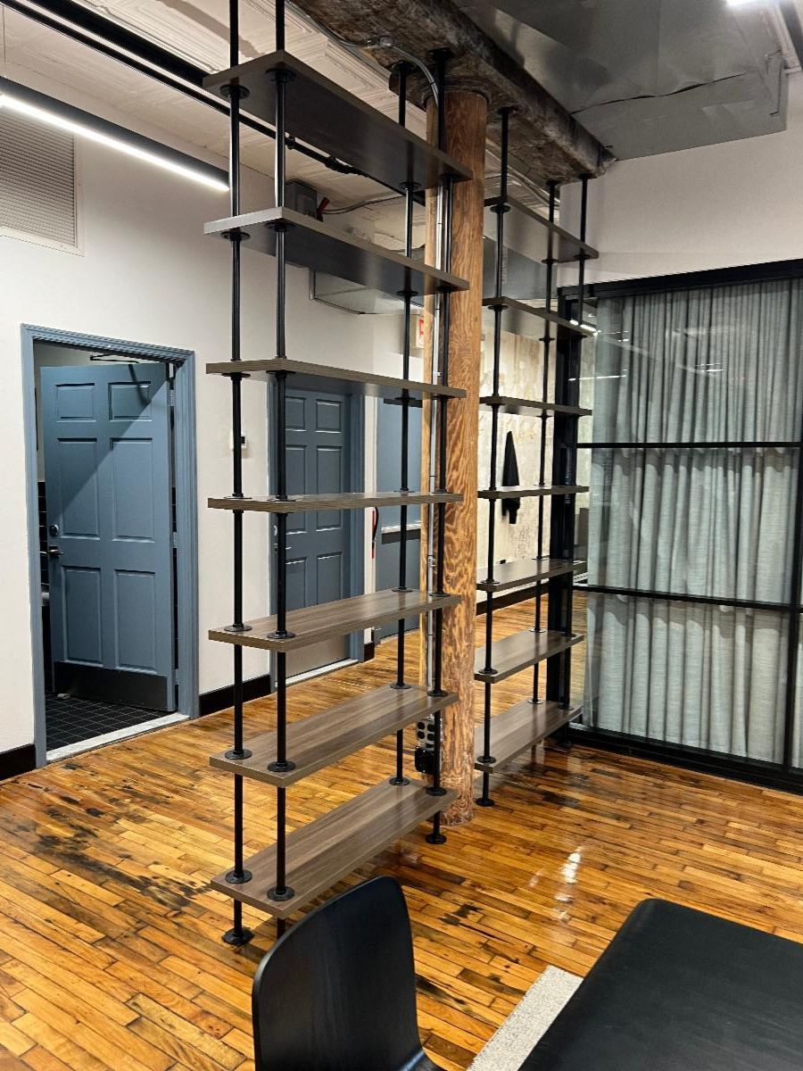 Industrial-style shelving unit in a room with wood floors, blue door, and glass panel wall.