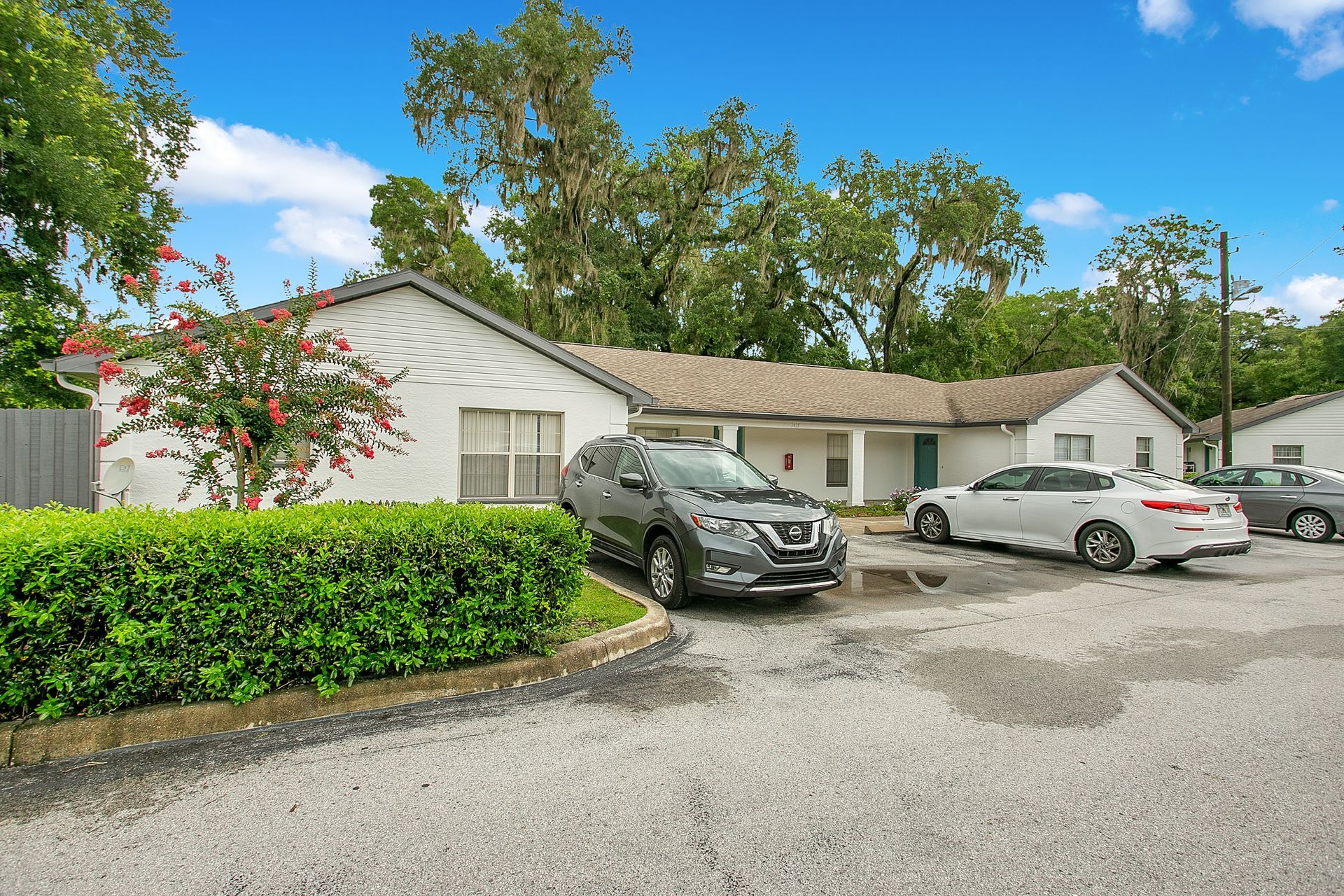 A row of cars are parked in front of a house.