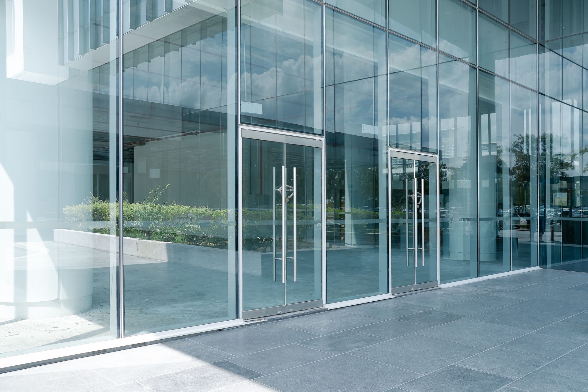 Modern commercial glass storefront entrance with sliding glass doors and large glass panels.