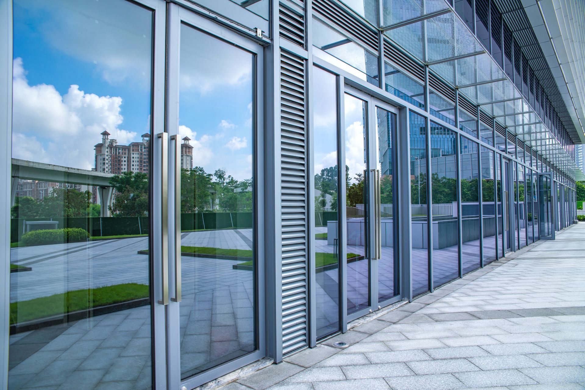 A modern glass building facade reflecting nearby greenery. A modern glass building facade reflecting nearby greenery.