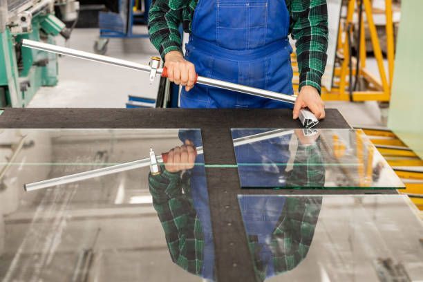 Close-up of a glazier from AAA Metal and Glass Inc. providing custom-cut glass services on a wooden