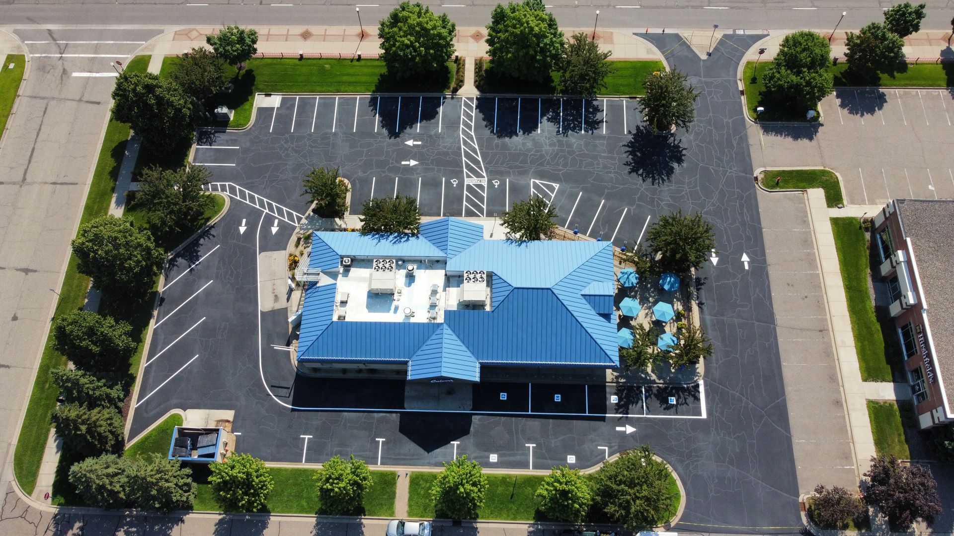An aerial view of a parking lot with a building in the background.