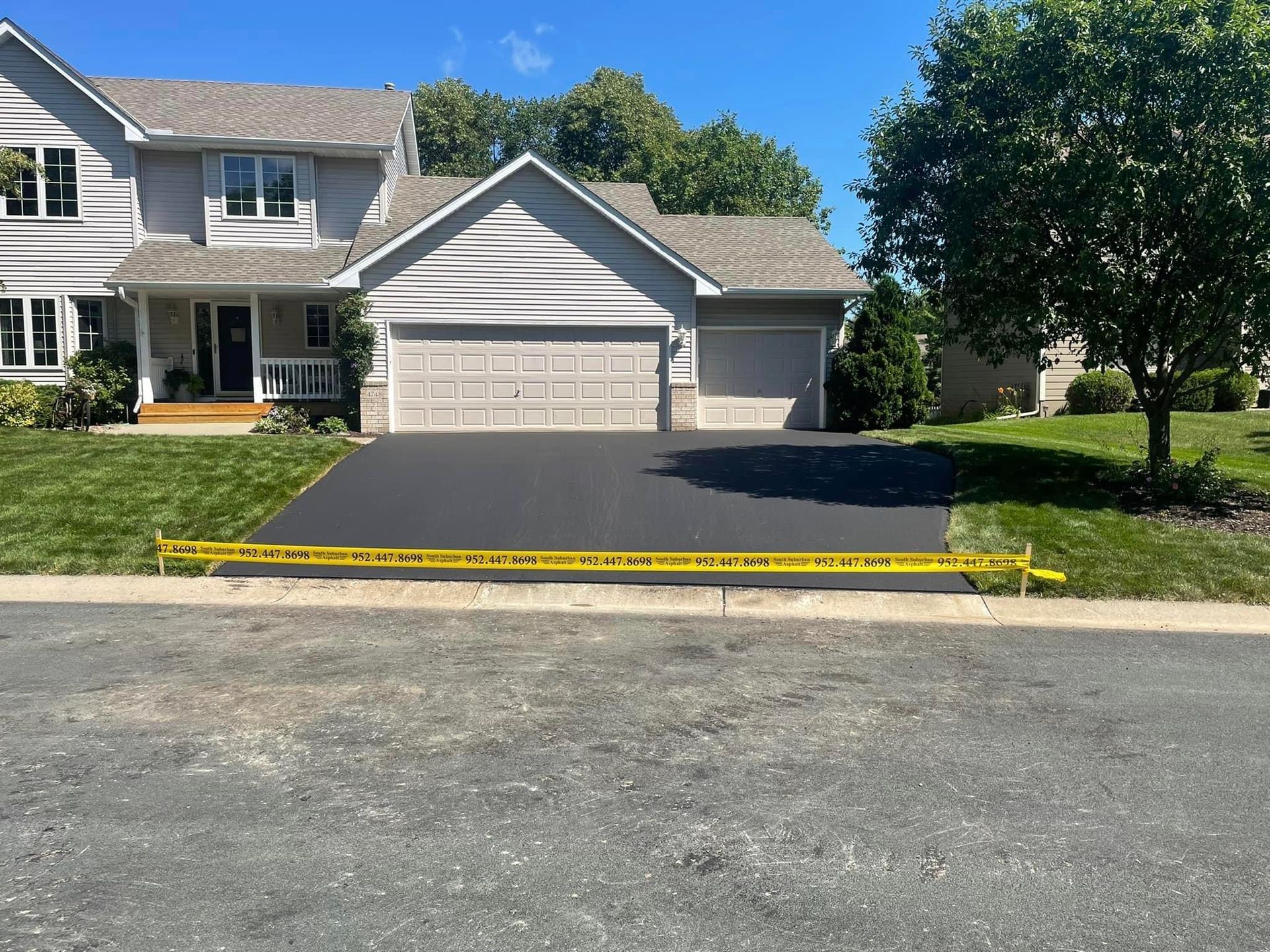 A large white house with a black driveway in front of it.
