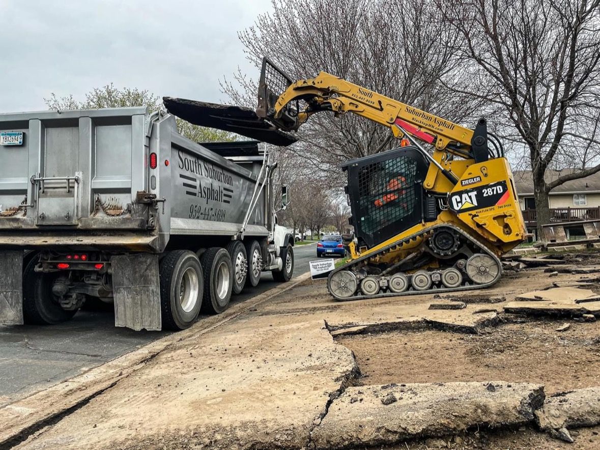 A dump truck is being loaded with dirt by a bulldozer.
