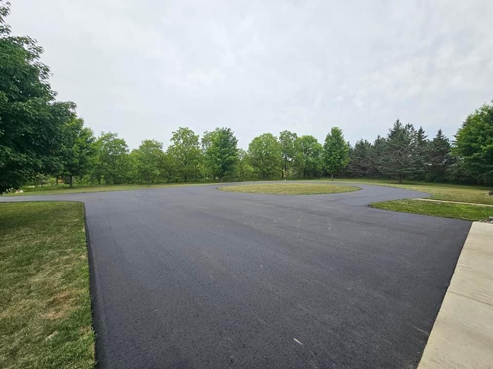A large empty parking lot surrounded by trees and grass.