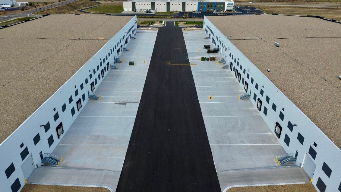 An aerial view of a parking lot with a building in the background.