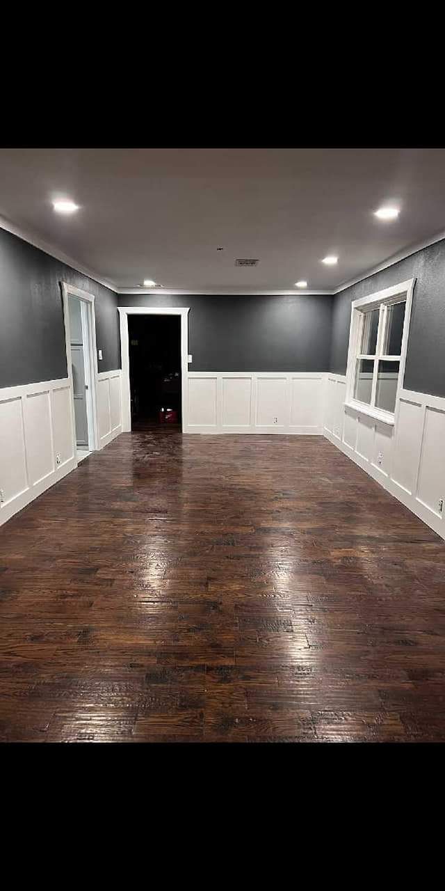 A large empty room with hardwood floors and gray walls.