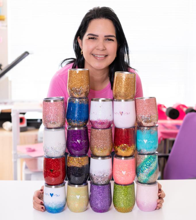 Una mujer está sentada en una mesa sosteniendo una pila de copas de vino.