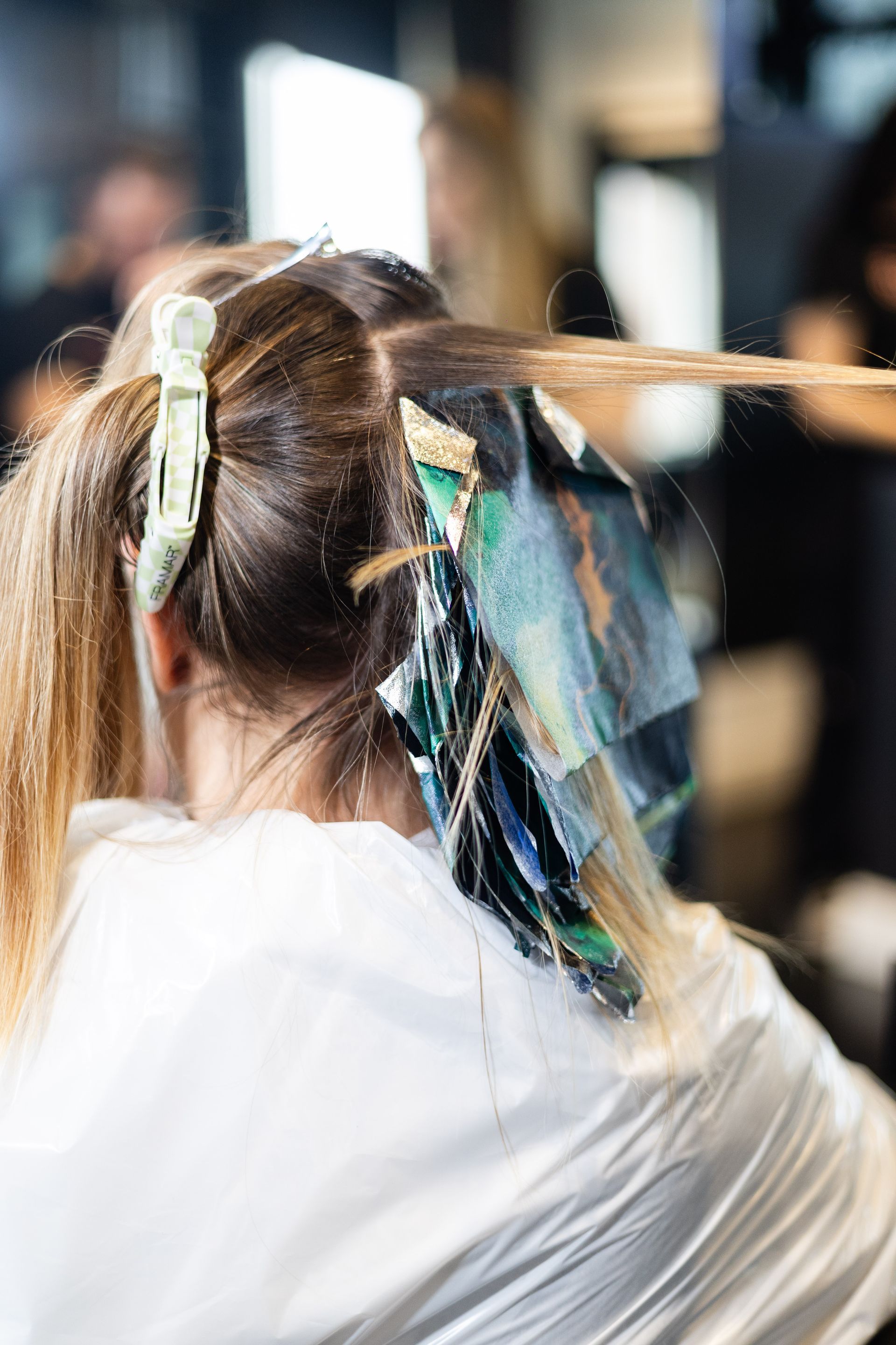 Un professionista con indosso guanti rosa utilizza un dispositivo cosmetico portatile per trattare il cuoio capelluto di una persona.