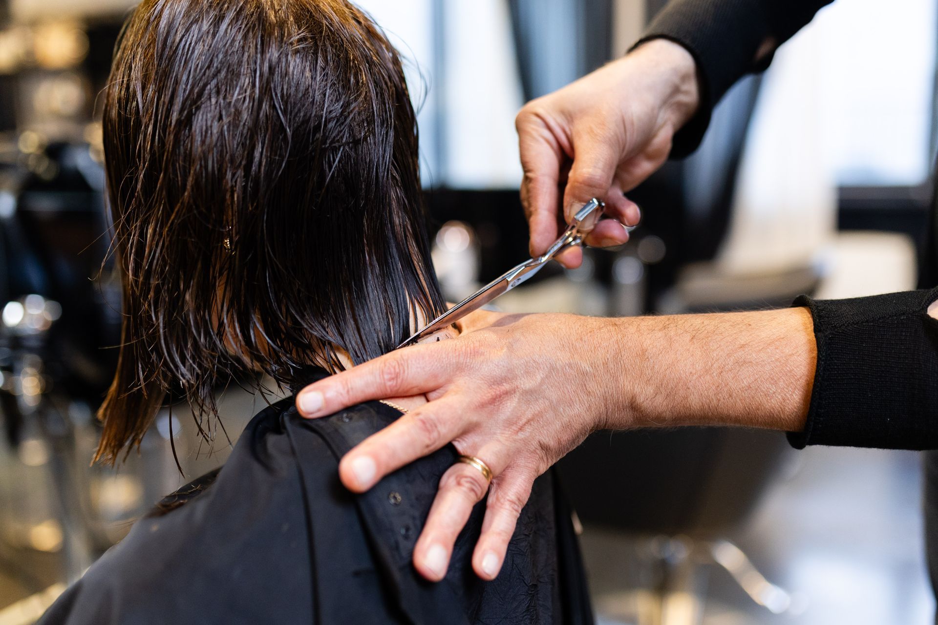 Un professionista con indosso guanti rosa utilizza un dispositivo cosmetico portatile per trattare il cuoio capelluto di una persona.