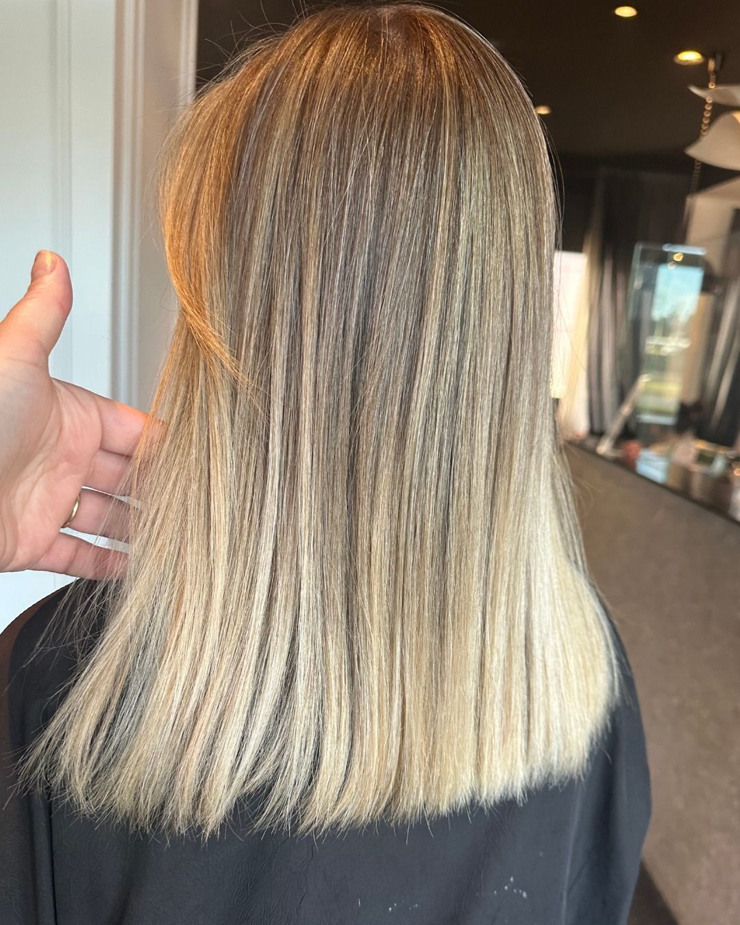 Una persona tiene in mano dei capelli che sono stati acconciati con un ferro arricciacapelli per creare un motivo ondulato e texturizzato.