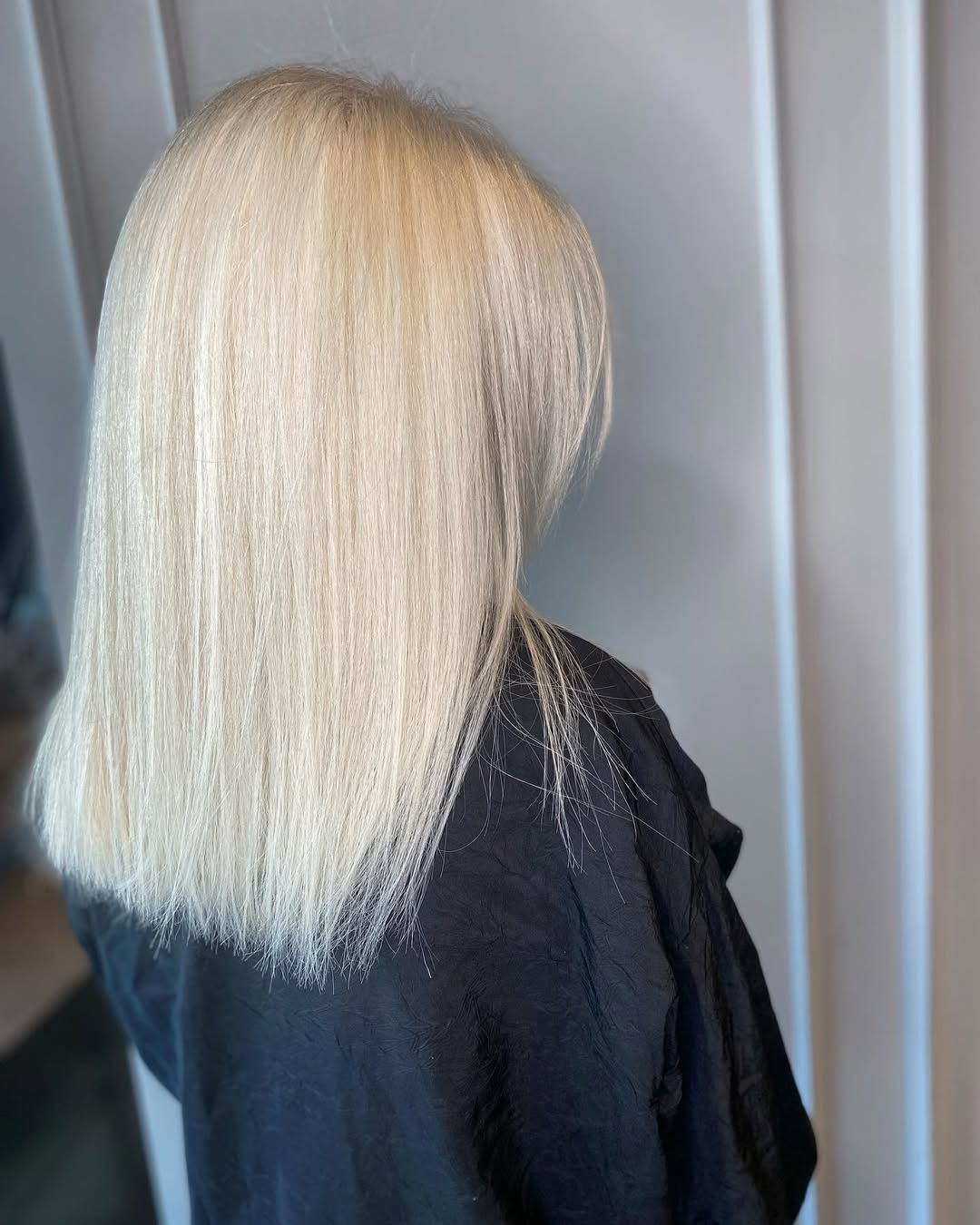 Una persona con capelli lisci, biondo platino, lunghi fino alle spalle, vista di spalle.