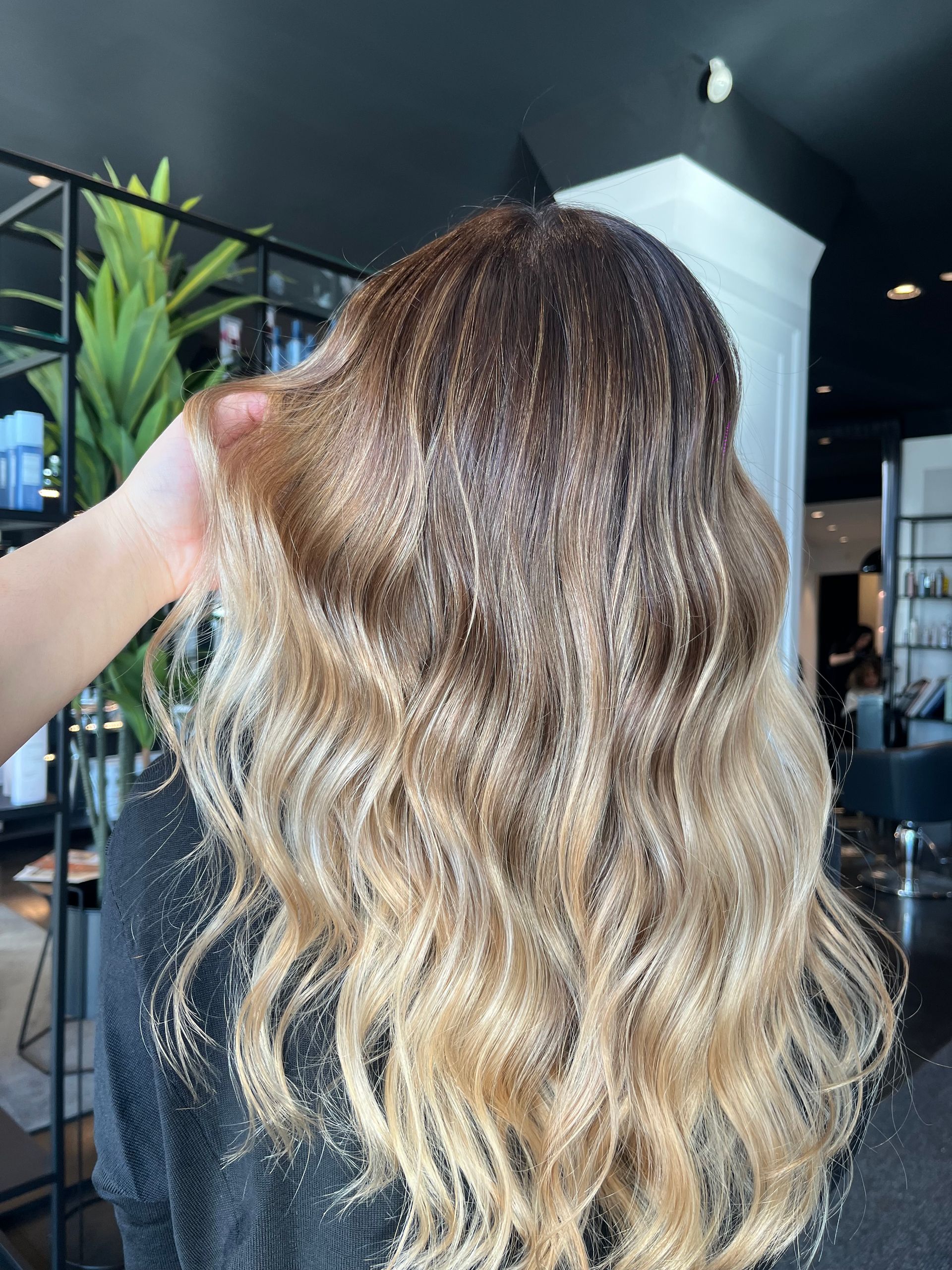 Capelli mossi con una transizione di colore ombré dal castano scuro al biondo chiaro, realizzata in salone.