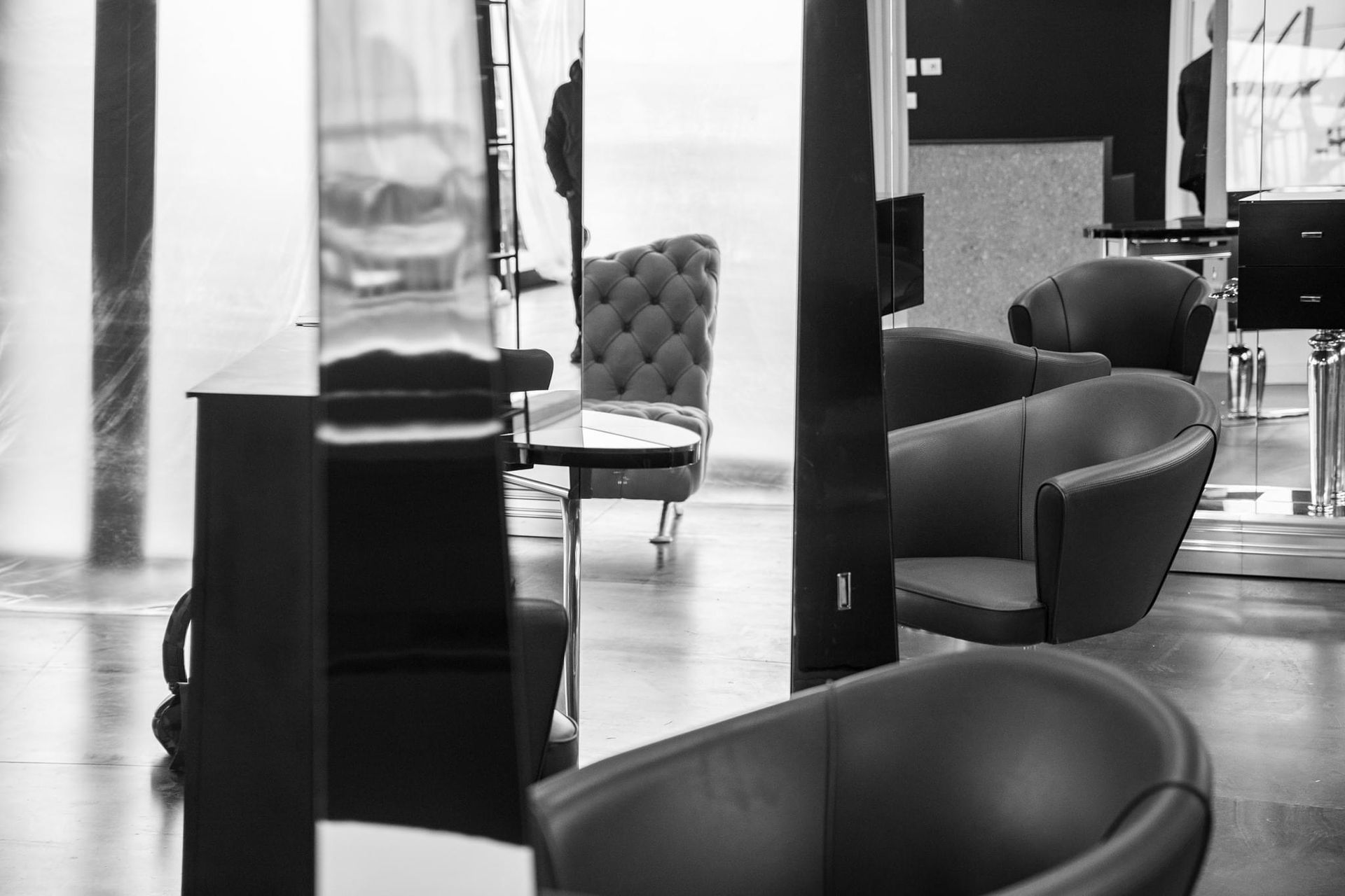 Foto in bianco e nero di un moderno salone di bellezza con diverse poltrone in pelle e grandi specchi.