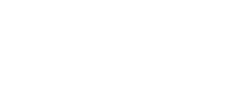 Una persona con un grembiule blu, in piedi dietro un bancone, tiene in mano un cannello da cucina per caramellare un dessert in una ciotola.