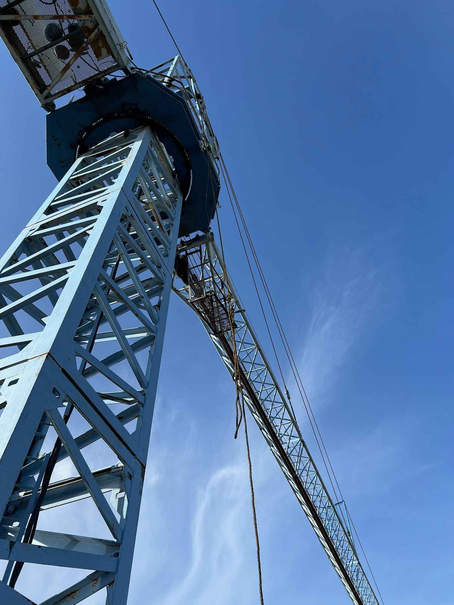 Blue construction crane against a clear, blue sky.
