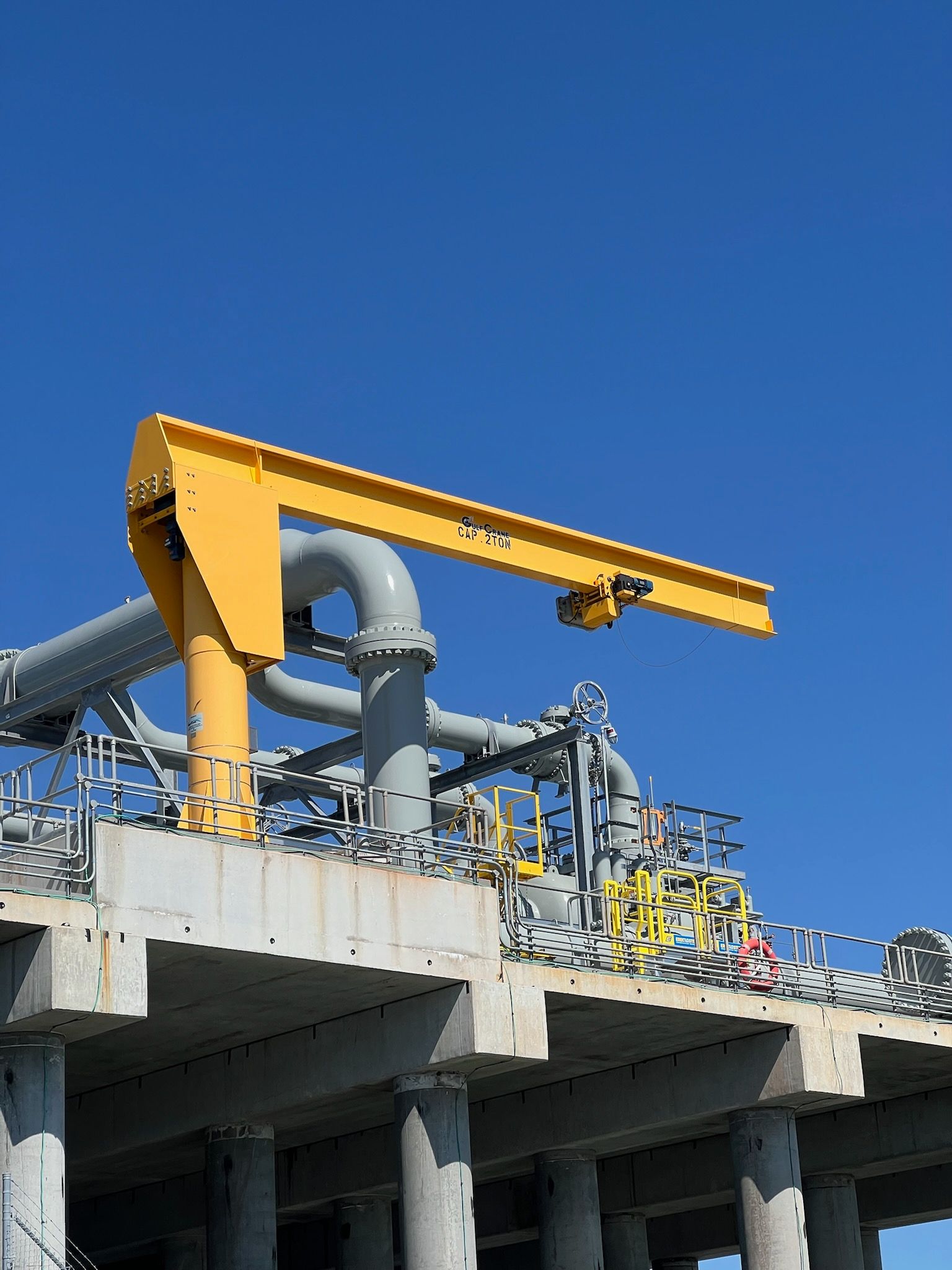 Yellow crane on industrial structure against a blue sky.