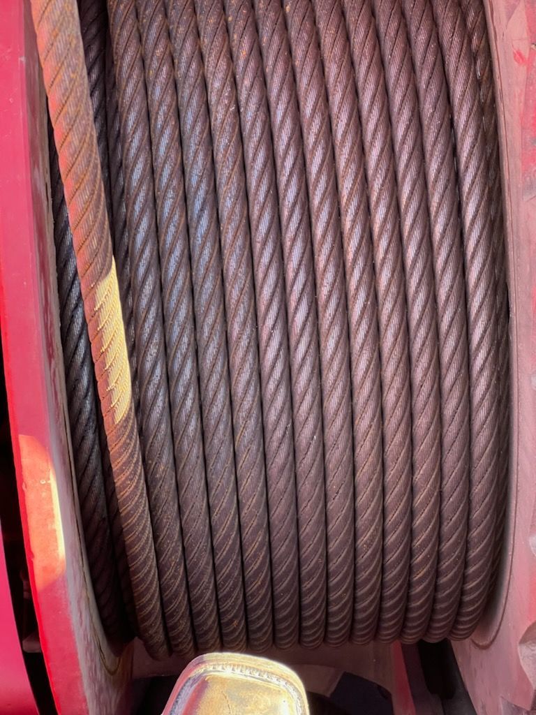 Spool of coiled steel cable, silver-gray in color.