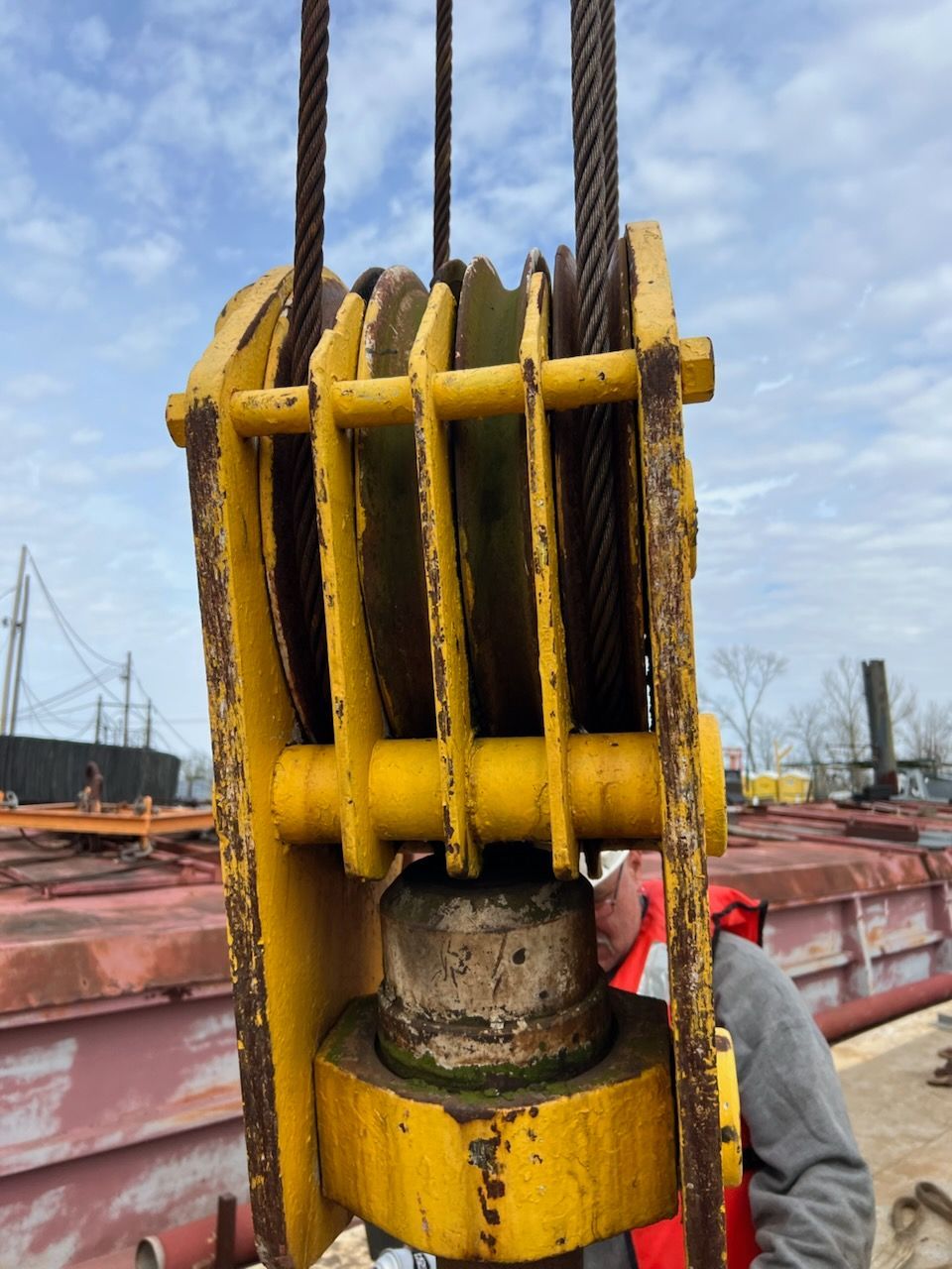 Yellow pulley system with steel cables, outdoors. A person in red visible.