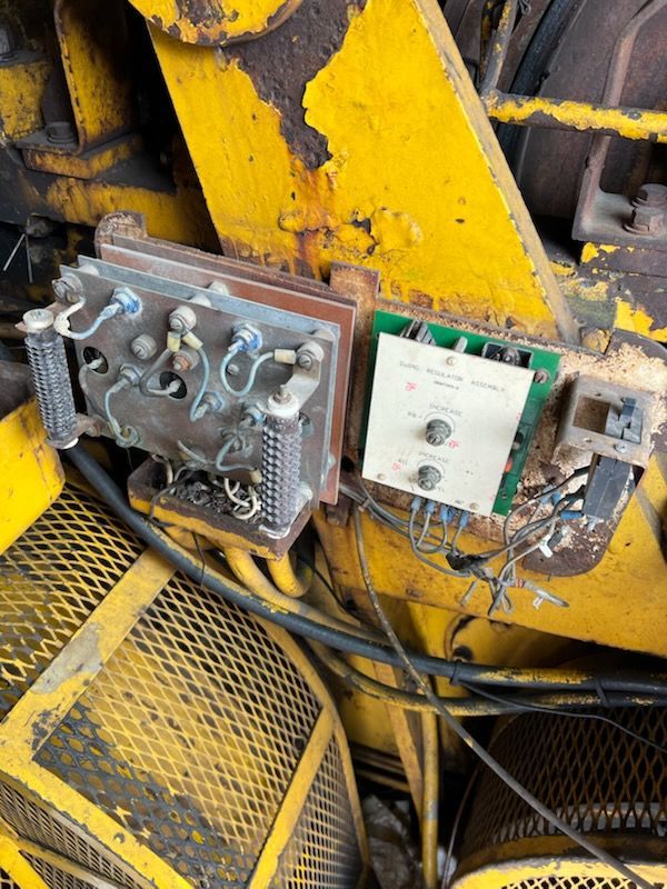 Electrical components with wires and dials mounted on yellow machinery.