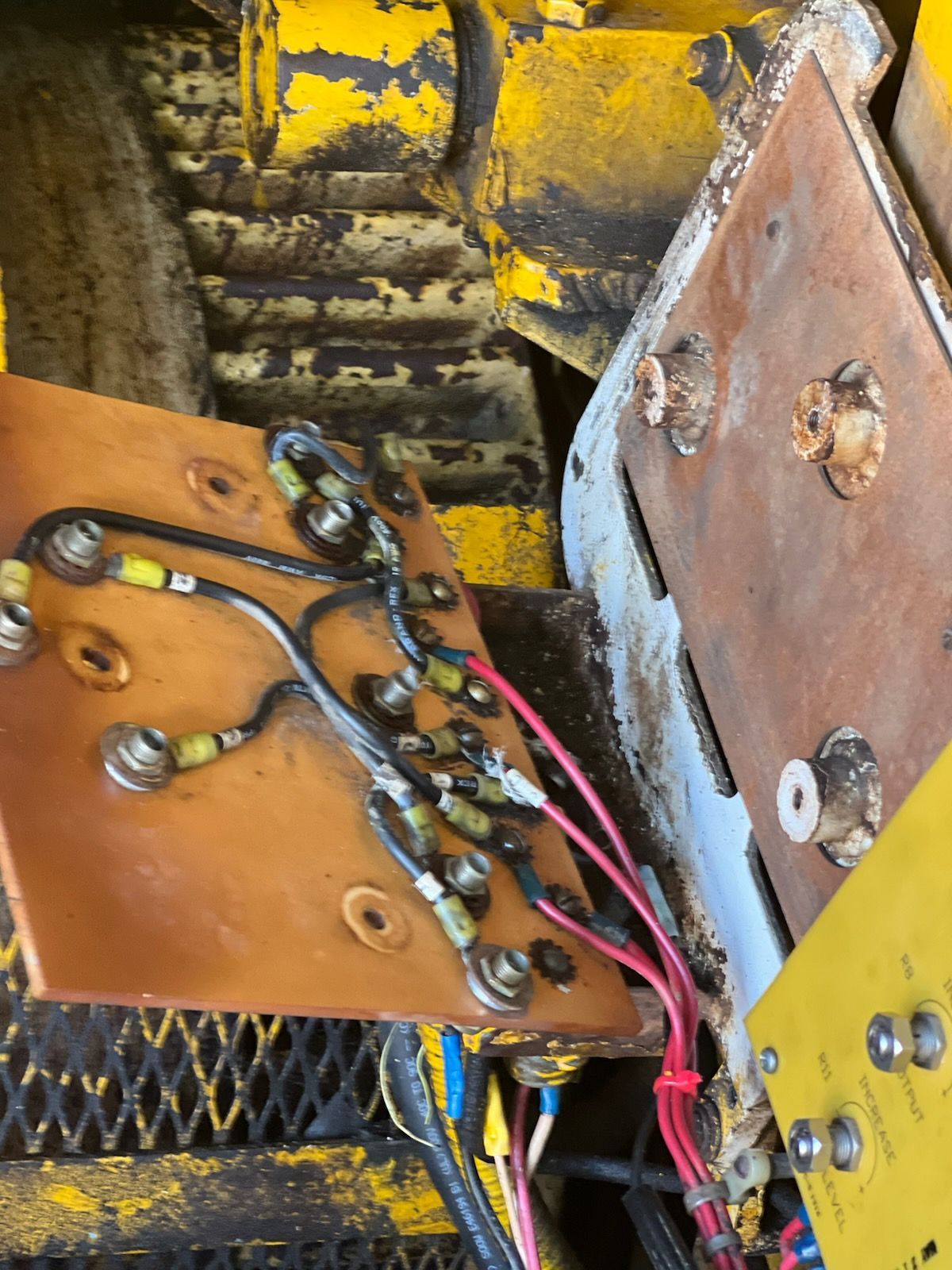 A circuit board with connected wires, mounted on machinery. Wires are red, yellow and black.