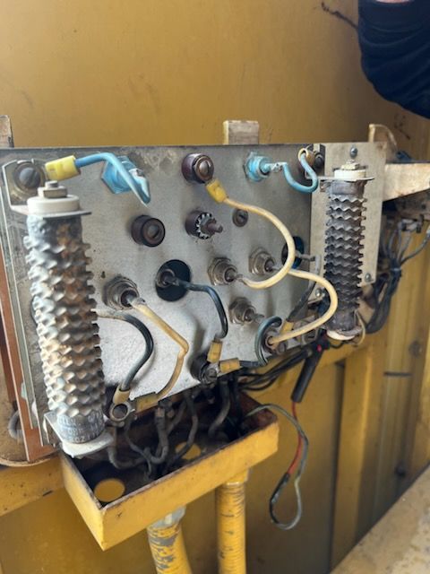 Control panel with wires, connectors, and ceramic resistors on a yellow surface.