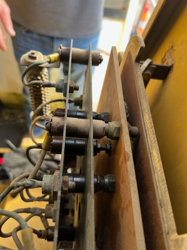 Close-up of electrical components with wires and bolt connections on yellow equipment.