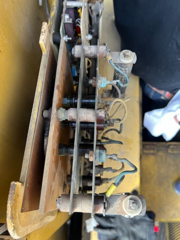 Yellow machinery electrical components. Cylindrical insulators, wires connected to various terminals.