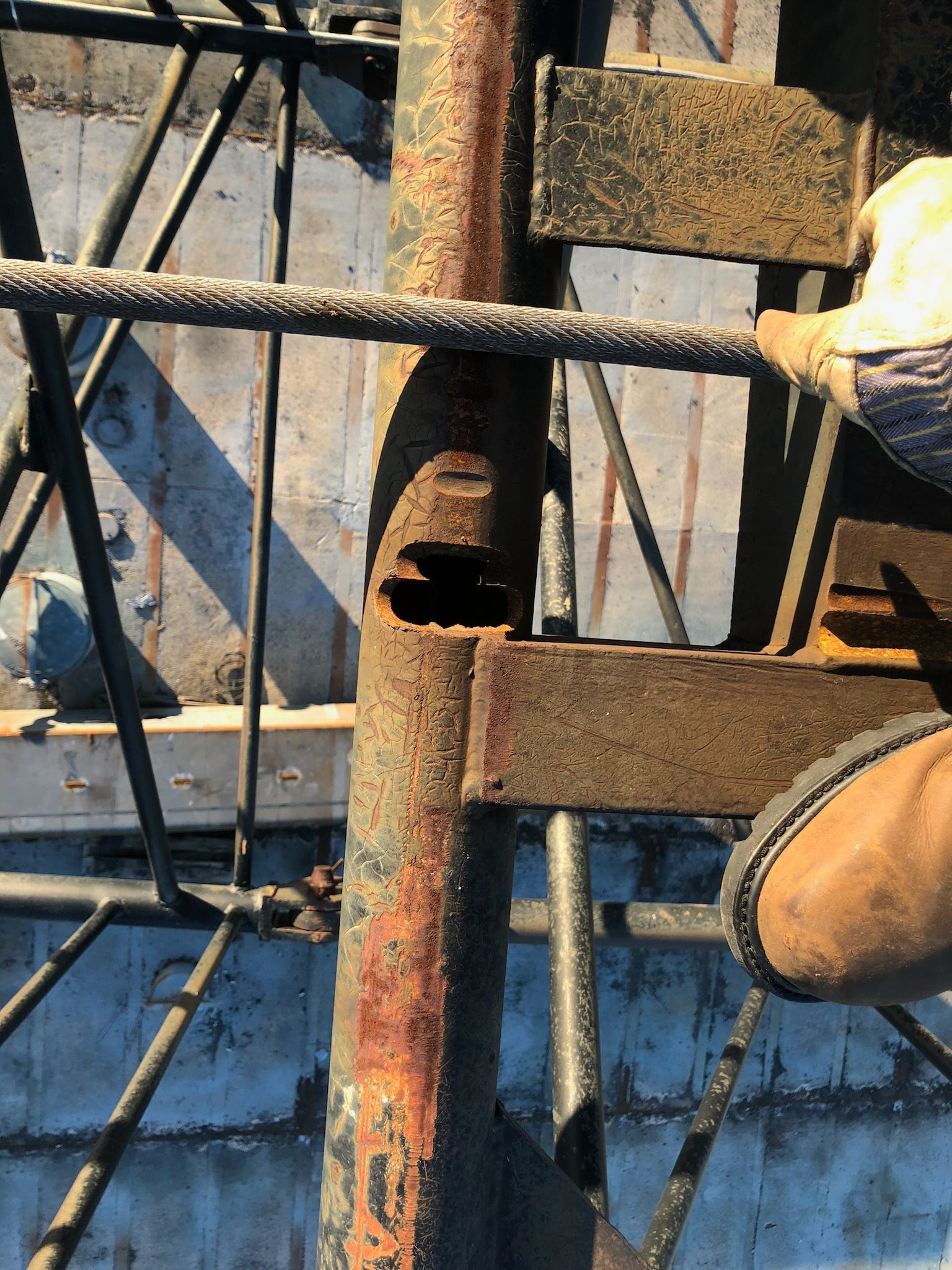 Rusty metal beam with a large hole, part of a deteriorating industrial structure.