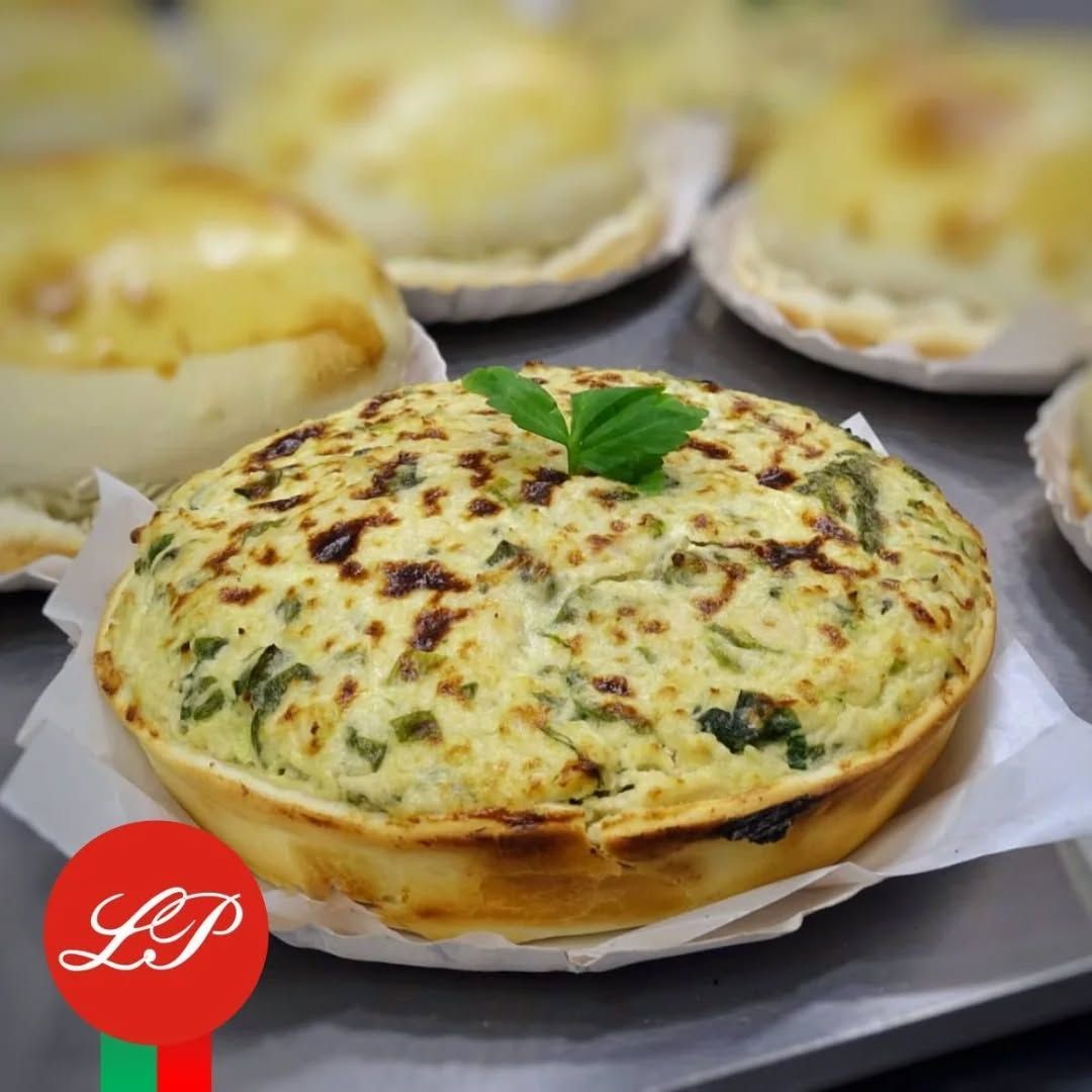 Quiche sabrosa con corteza dorada, rodeada de pasteles similares.